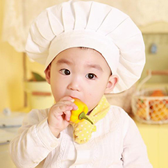 Een kind met een koksmuts op en een paprika aan het eten is